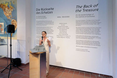 Artist stands before the introductory text in the exhibition space and gives a short lecture