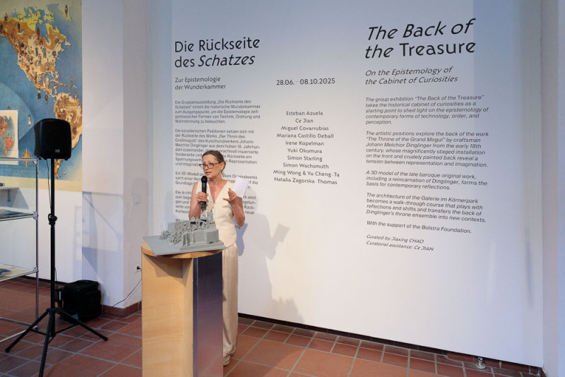 Künstlerin steht vor dem Einführungstext im Ausstellungsraum und hält einen kurzen Vortrag