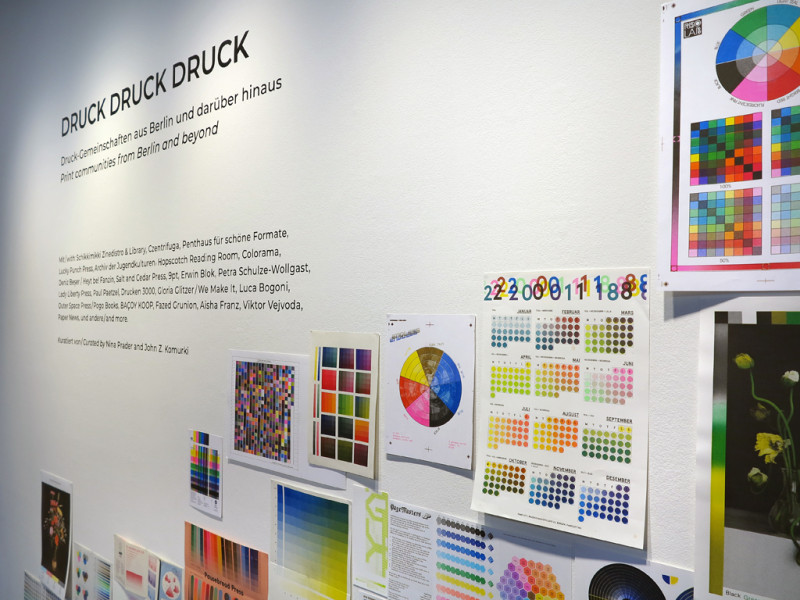 Wandtext der Ausstellung und verschiedene Blätter mit Darstellungen von Farbpaletten.
