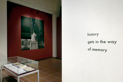 Im Vordergrund eine weiße Wand mit der Schrift 