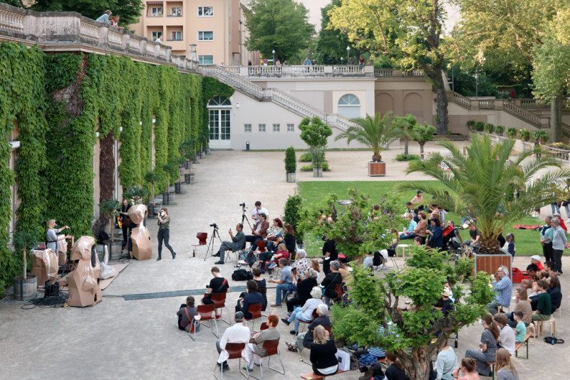 viele Menschen sitzen auf der Terrasse bei der Eröffnung der Ausstellung 