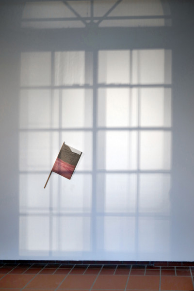 Magazine TIEMPO MUERTO (Dead Time) tied around a stick and attached to the wall for viewing. A large part of the wall is depicted with a shadow in the form of an arched window