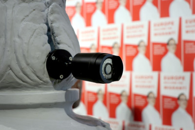 A grey column with plaster casts, CCTV cameras and monitors.