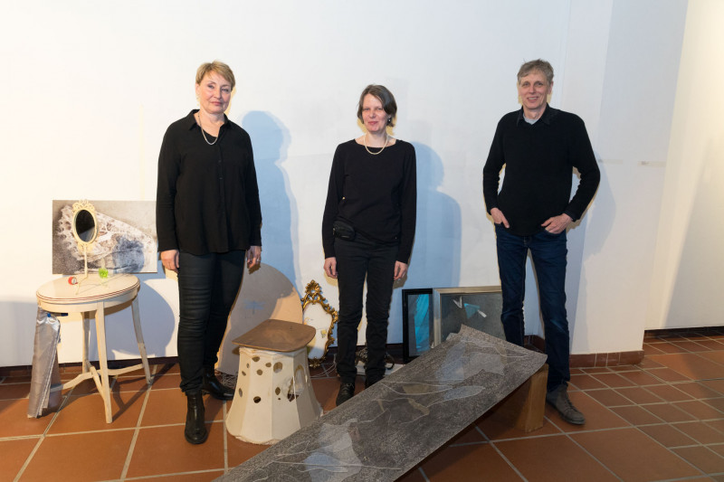Die drei Künstler:innen der Ausstellung stehen inmitten einer Installation.
