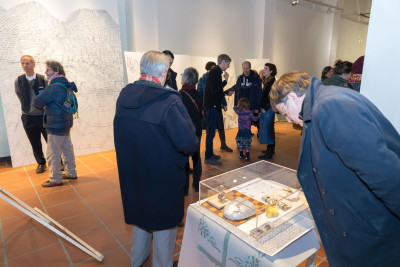 Besucher:innen der Ausstellung betrachten die Arbeiten oder unterhalten sich.