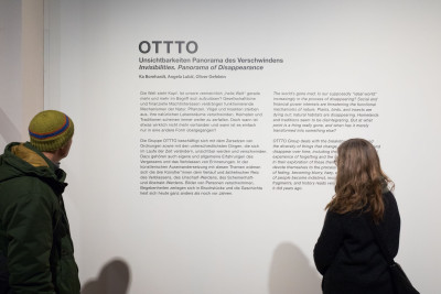 Zwei Besucher:innen lesen den Wandtext der Ausstellung.