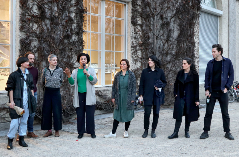 8 Personen stehen vor der Galerie im Körnerpark. In der mitte hält Yolanda Kaddu-Mulindwa das Mikrofon.