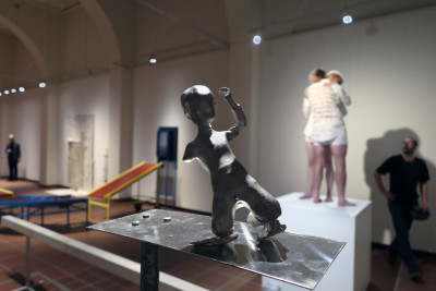 Eine kleine als Kind erkennbare Figur aus Zinn balanciert auf den Knien und scheint nach hinten zu kippen.