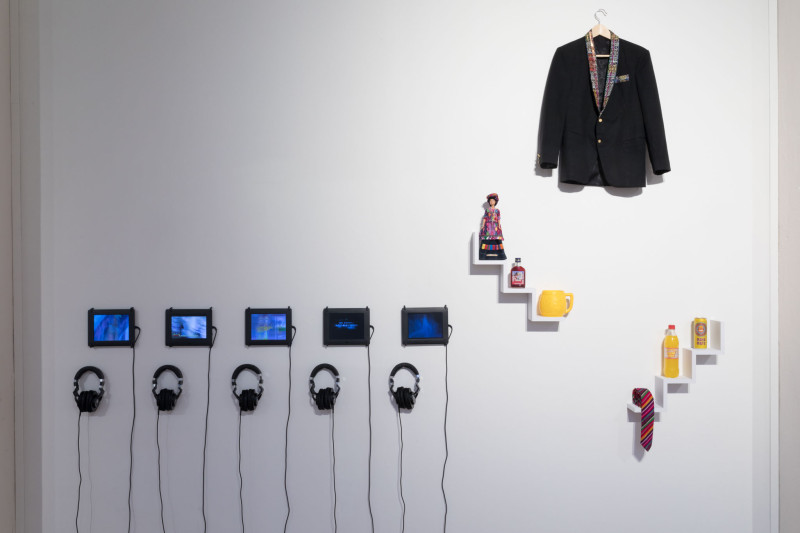 Es hängen kleine Bildschirme mit Kopfhörern, eine Jacke und Gegenstände an der Wand.