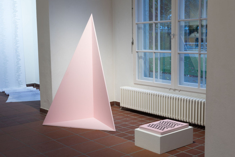 Rauminstallation. Eine geöffnete, rosa, dreieickige Pyramide  steh im Raum.
