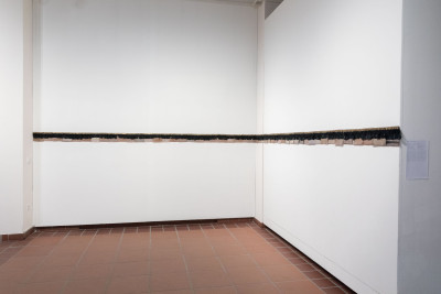 A straight line of fabric strips is attached to the wall.