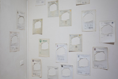 Old documents with houses cut out, hang on the wall.