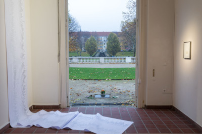 A long big list hangs on the wall, it is partly on thew floor. The window is open.