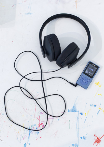 An MP3 player with headphones connected lies on a surface