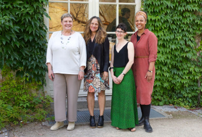 Four women in full view. They are standing next to each other and smiling