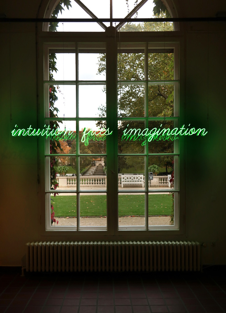 Vor einem großen Fenster, das raus in den Körnerpark blickt, ist ein neongrüner Leuchtschriftzug mit den Worten „intuition frees imagination“ (Intuition befreit die Vorstellungskraft) zu lesen.