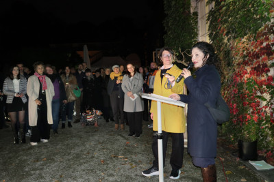 A group of people are gathered around a speaker holding a microphone