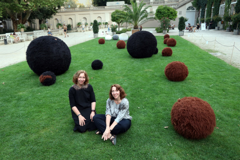 Die Künstlerinnen sitzen vor mit Fell überzogene Bälle auf der Wiese vor der Galerie im Körnerpark
