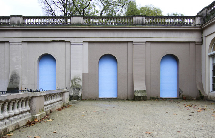 Im Körnerpark sind blaue Plakate in den Arkaden der Wand plakatiert.