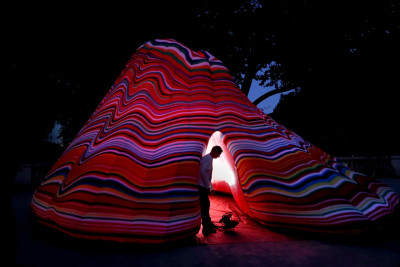 Ein bunter aufgeblasener Vulkan steht im Park bei Nacht.