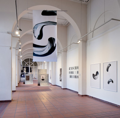 Galerieraum mit weißen Bögen und abstrakten schwarz-weißen Kunstwerken an den Wänden