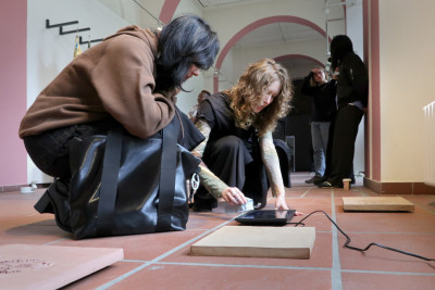 The artists are bent over a work of art in the exhibition.