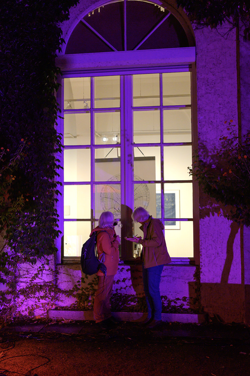 Ein kulinarischer Performance-Abend zum 40-jährigen Jubiläum der Galerie im Körnerpark,während zwei Besicherinnen schauen die fenster der gallerie rein und bestaunen die Agens Denes Ausstellung