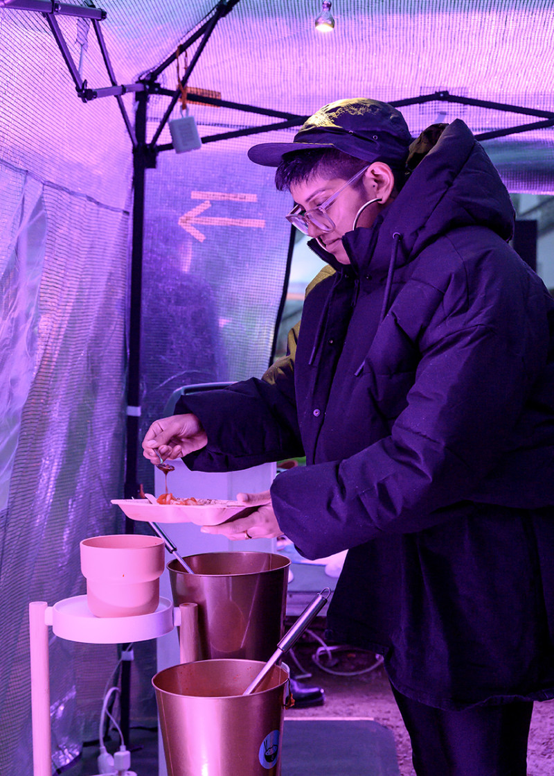 Besuchende füllt sich Essen auf, während der Eröffnung des Jubiläums mit partizipativer Koch- und Essperformance
