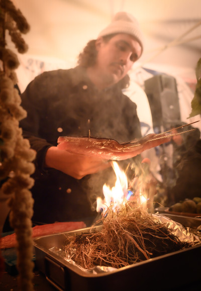 Dauwd Al Hilali from the collective African Acid is the Future grills a fish over an open fire